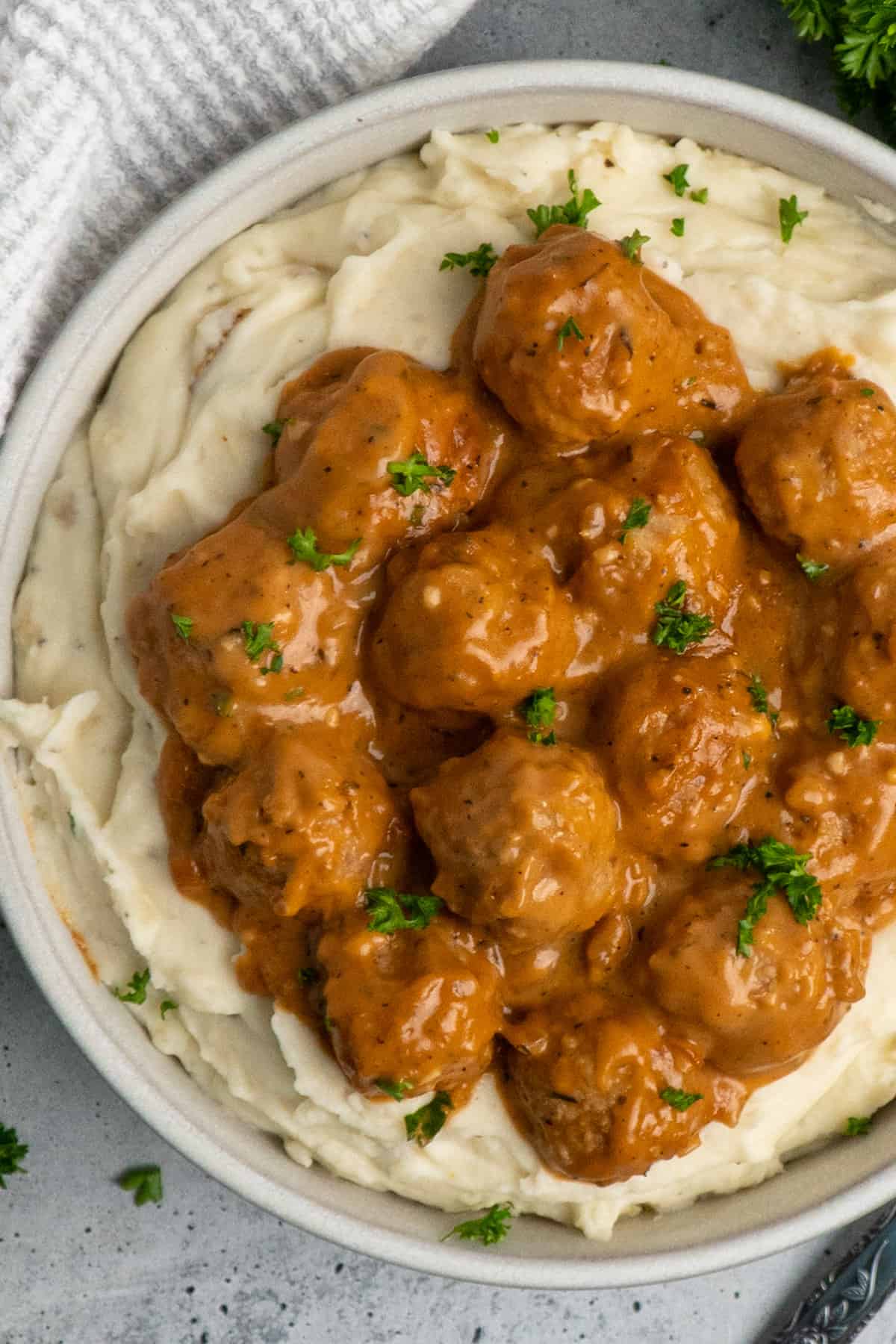 Crock Pot meatballs and gravy over a bowl of mashed potatoes.