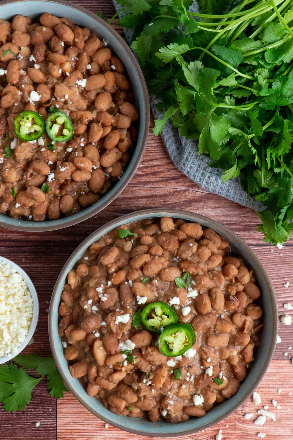Two bowls of pinto beans on a wood background.