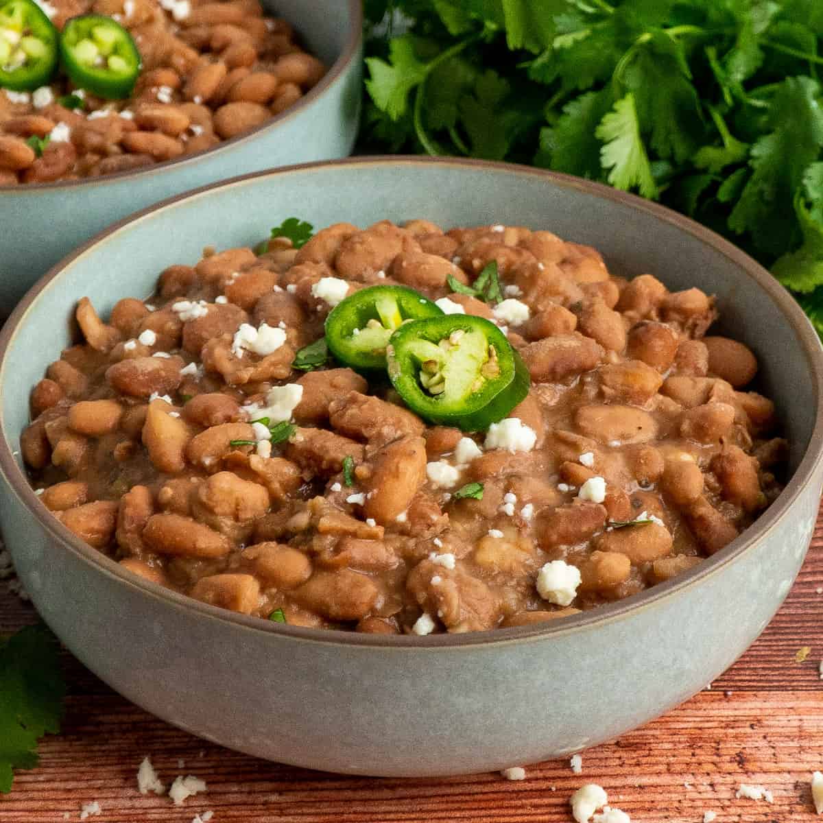 Pinto beans in a bowl garnished with cheese and jalapenos.