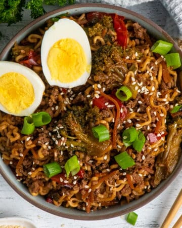 Slow cooker beef ramen noodles in a bowl garnished with two eggs.