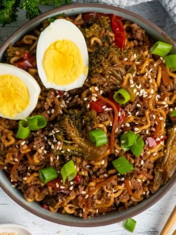 Slow cooker beef ramen noodles in a bowl garnished with two eggs.