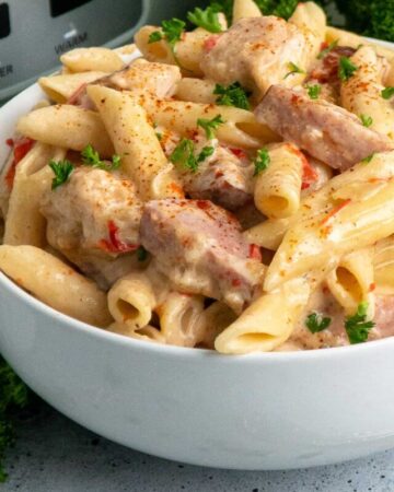 Close up of cajun chicken pasta in a white bowl.