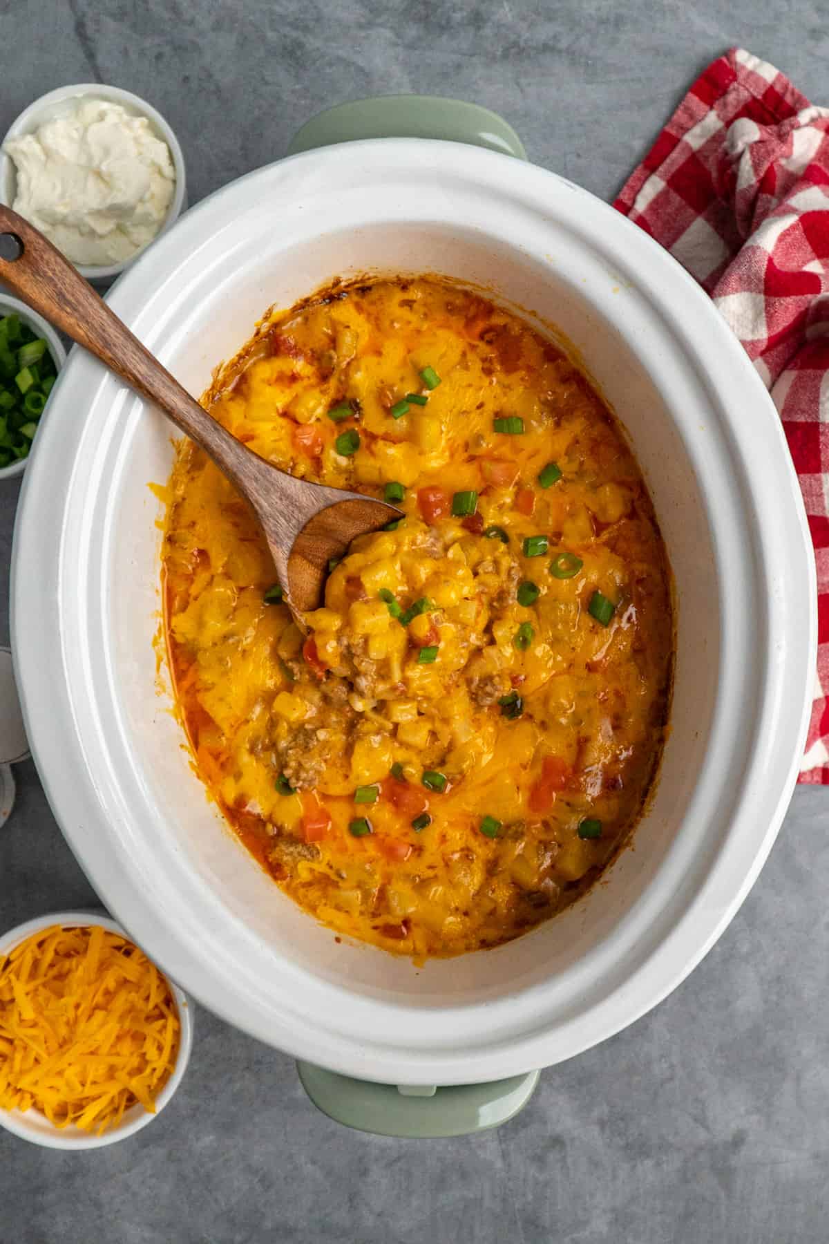 Overhead look at crock pot beefy potato taco casserole with a wooden spoon in it.