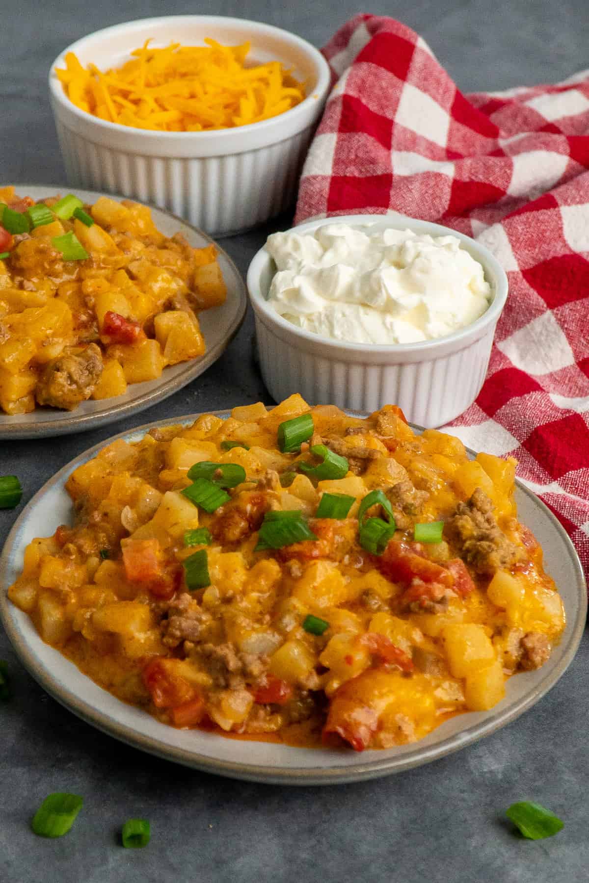 Two plates of beefy potato taco casserole garnished with green onions.