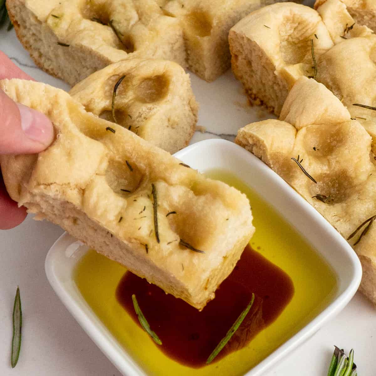 Focaccia bread being dipped into olive oil and balsamic vinegar.