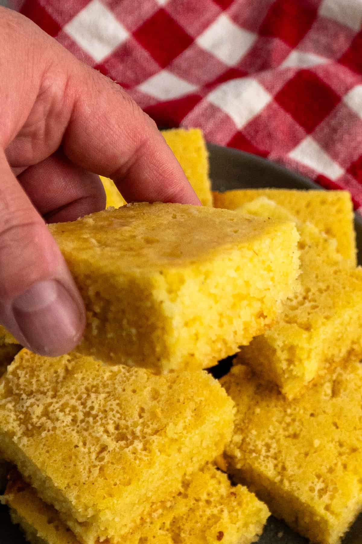 A hand holding a piece of cornbread.