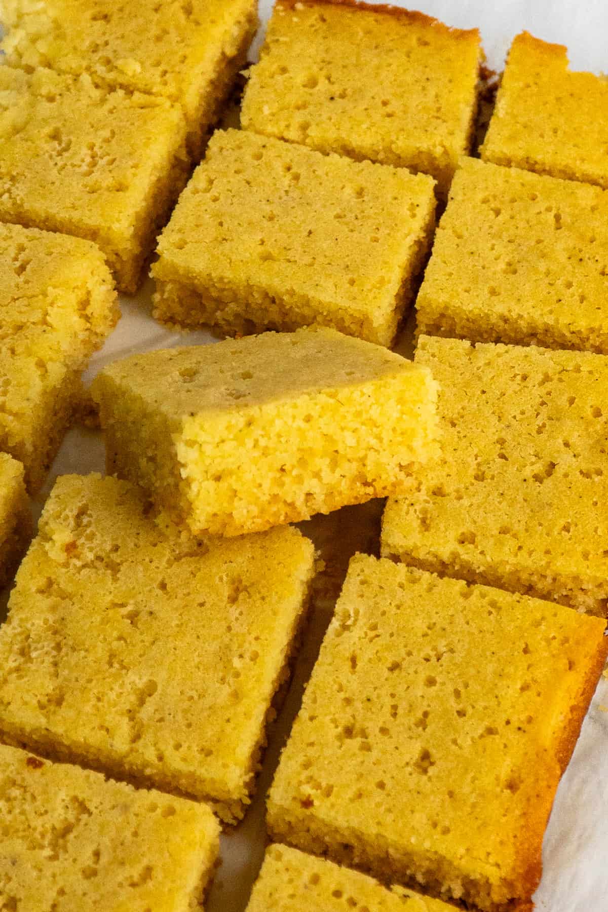 Cornbread cut into pieces on a piece of parchment paper.