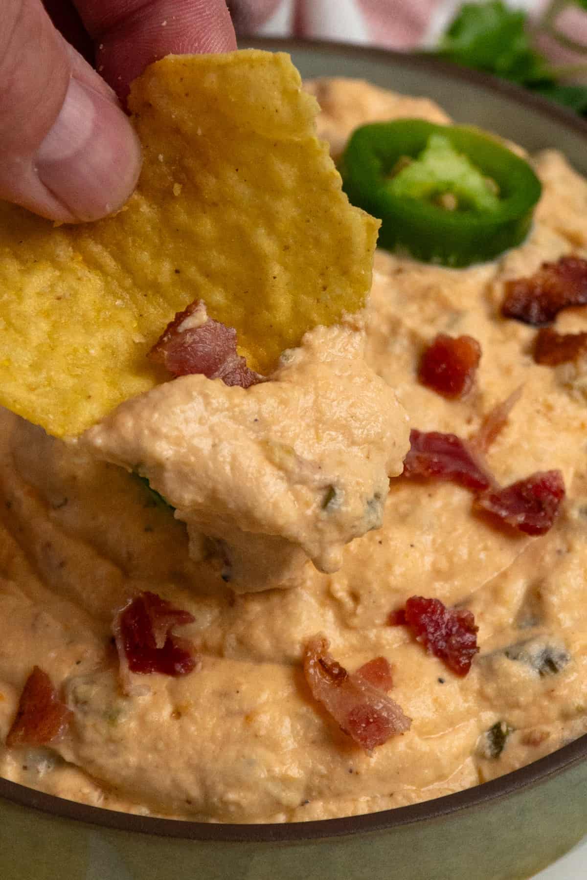 A chip with jalapeno popper dip on it.