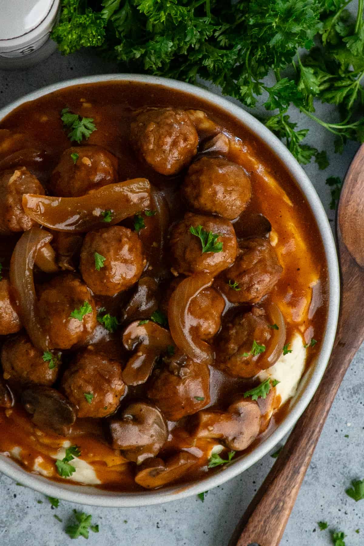 Overhead look at crock pot salisbury steak meatballs over a bowl of mashed potatoes.