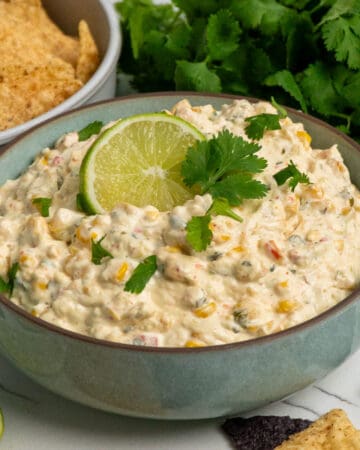 Crock pot street corn dip in a bowl garnished with a lime and cilantro.