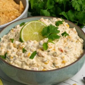 Crock pot street corn dip in a bowl garnished with a lime and cilantro.