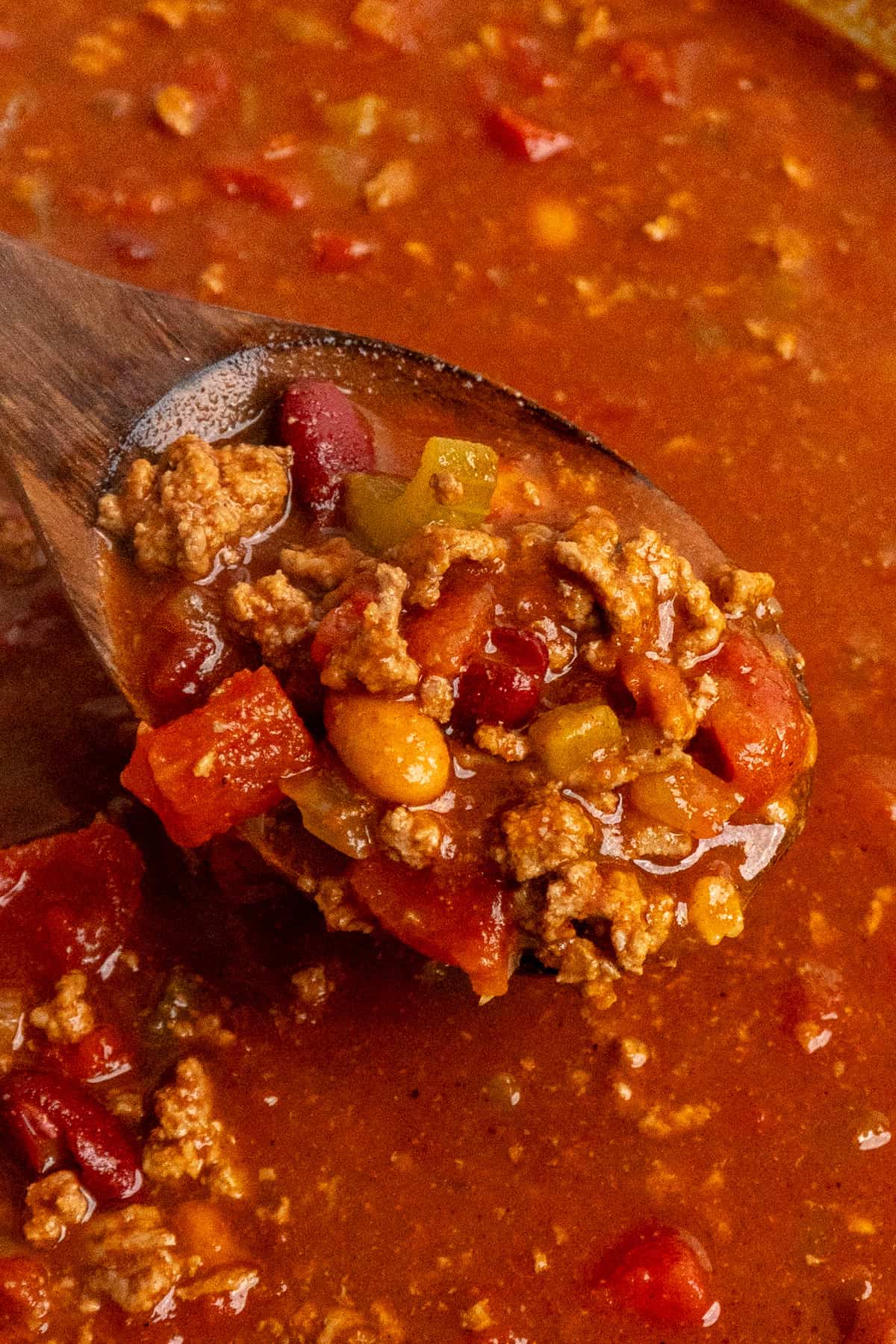 A wooden spoon holding a scoop of chili.