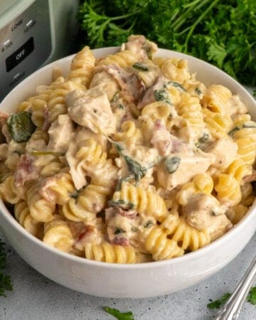 Close up of crock pot chicken bacon ranch pasta in a white bowl.
