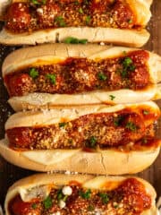 Overhead look of four crock pot meatball subs on a wood cutting board.