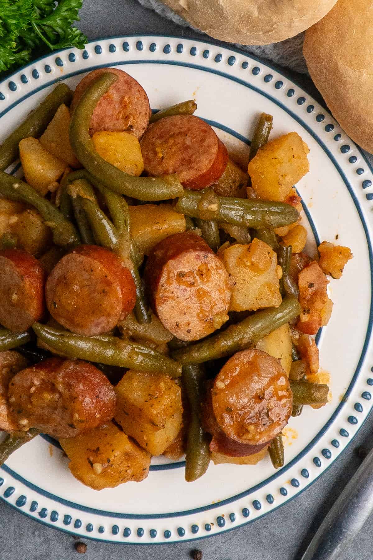 Overhead look at sausage potoatoes and green beans on a white plate.