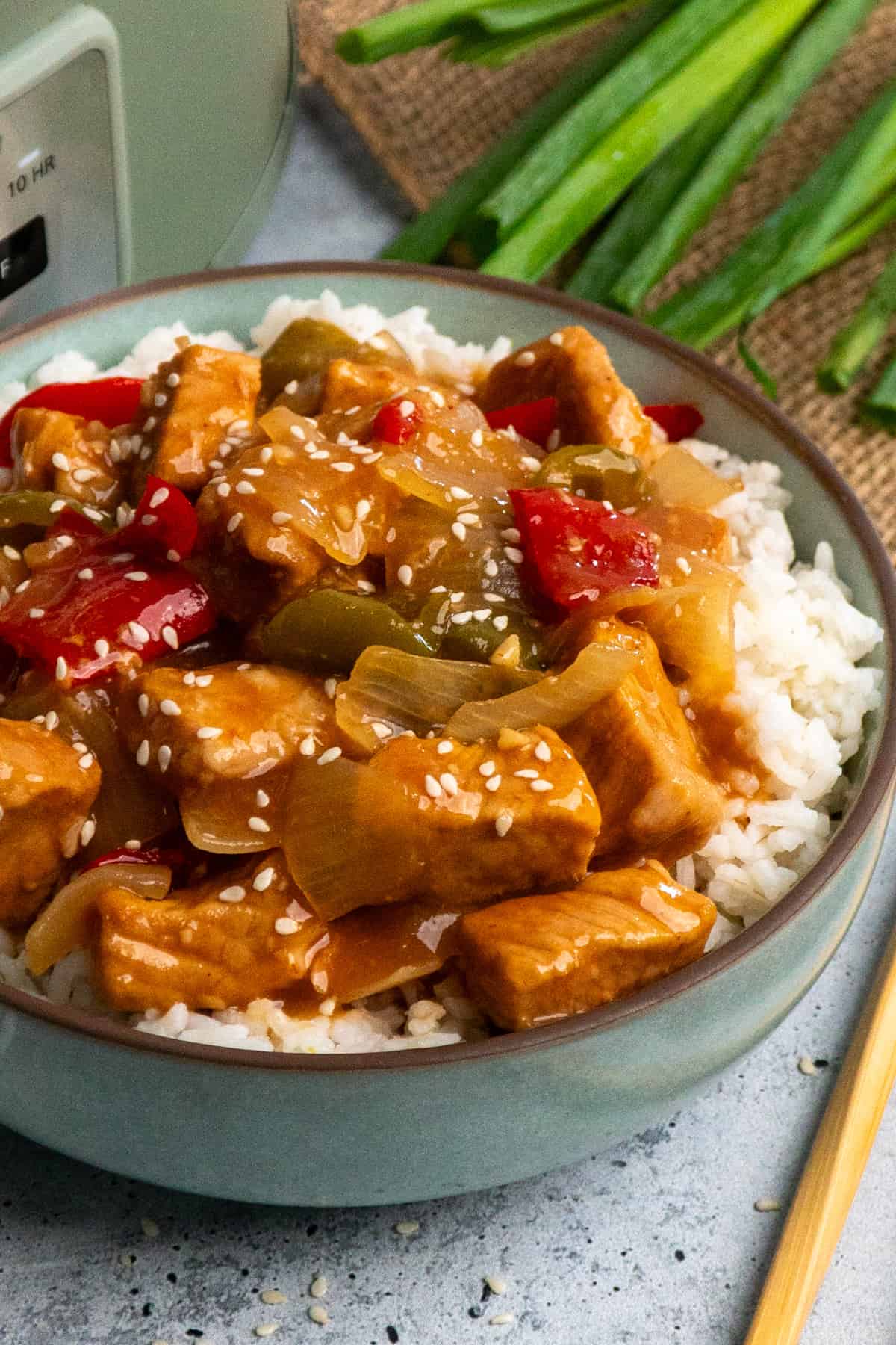 Close up of sweet and sour pork over a bowl of rice.