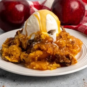 Close-up of crock pot apple cobbler with ice cream and caramel on top.