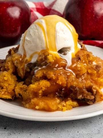 Close-up of crock pot apple cobbler with ice cream and caramel on top.
