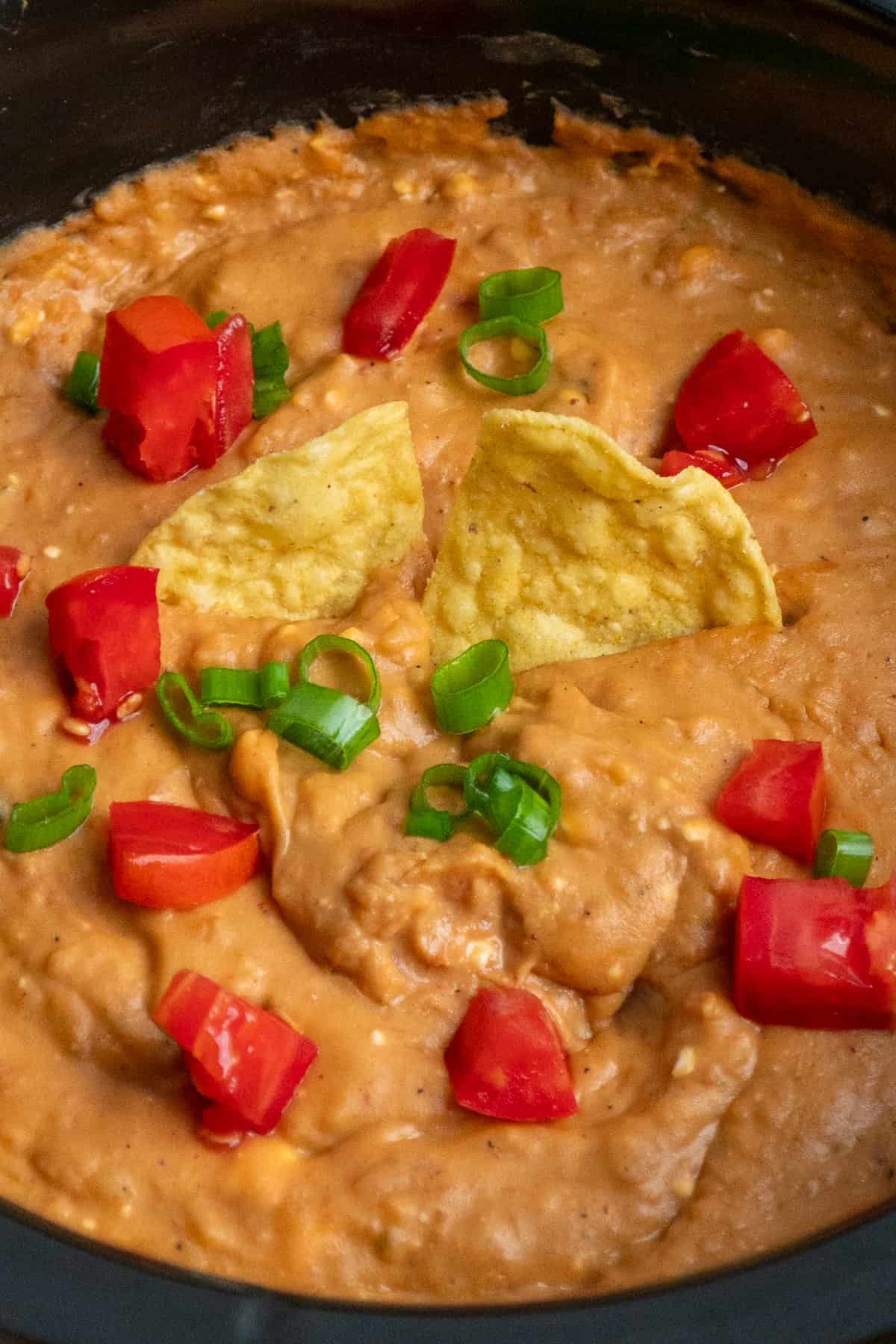 Bean dip with tomatoes and green onions on it.