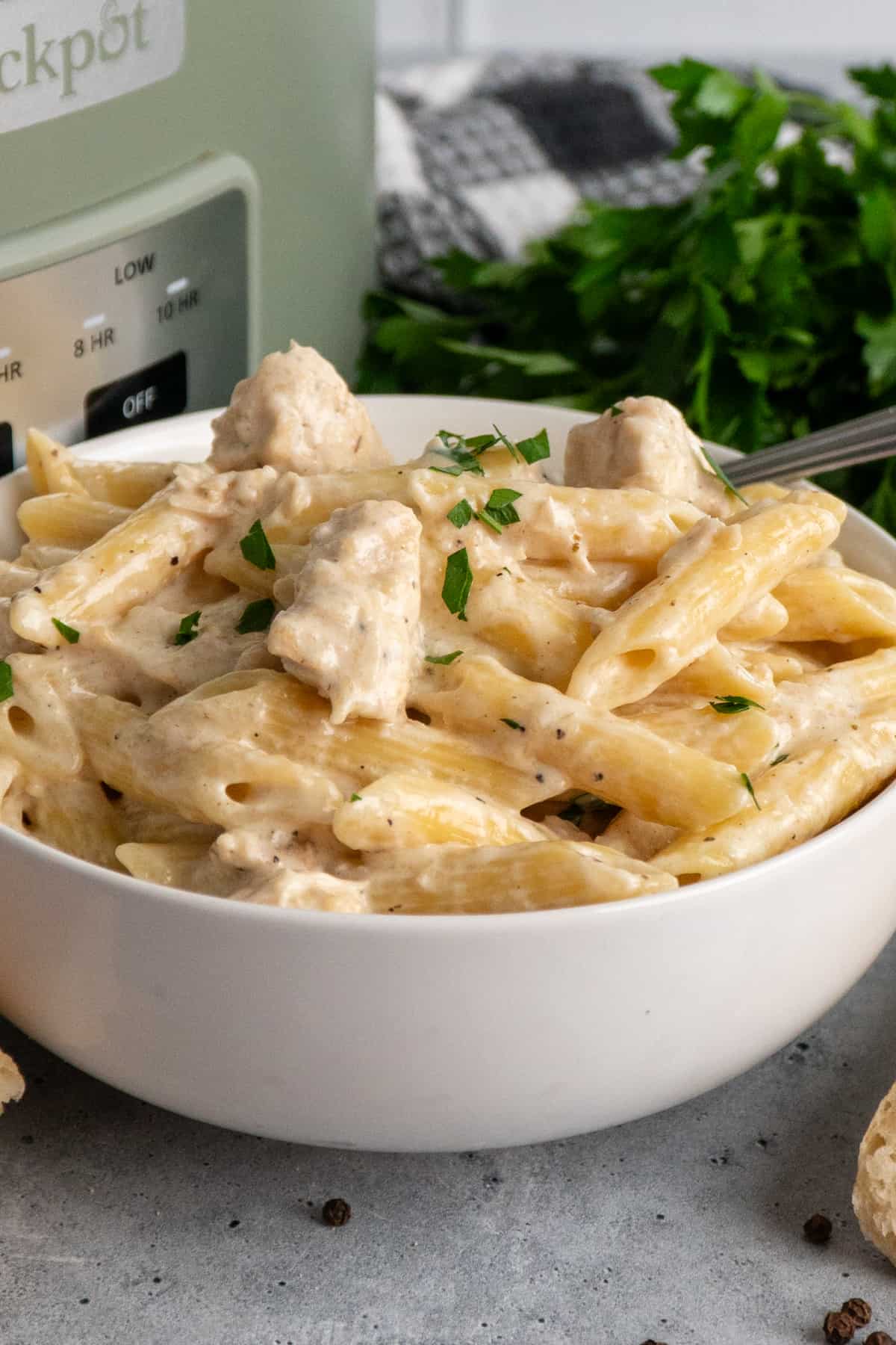 Close-up of chicken alfredo in a white bowl.