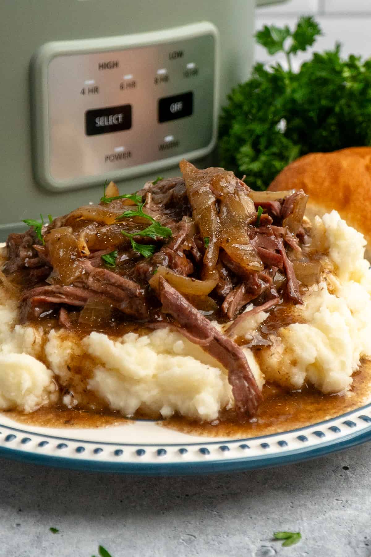 Close-up of French onion pot roast over a plate of mashed potatoes.