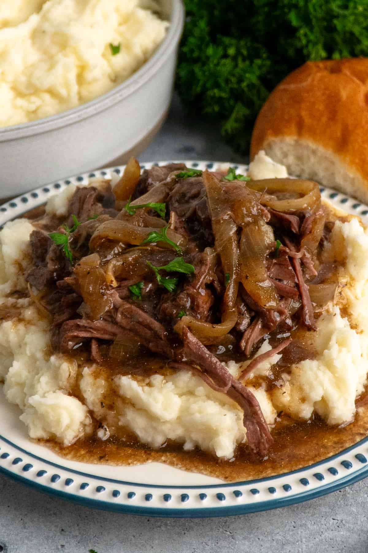 Close-up of French onion pot roast over a plate of mashed potatoes.