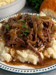 Close-up of French onion pot roast over a plate of mashed potatoes.