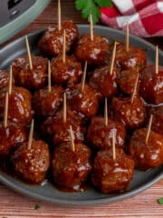 Close-up of BBQ meatballs on a plate with toothpicks in them.
