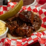 Close-up of crock pot burnt ends on Texas toast with a pickle.