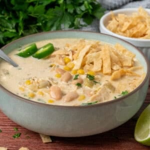 A bowl of crock pot white chicken chili garnished with tortilla strips.