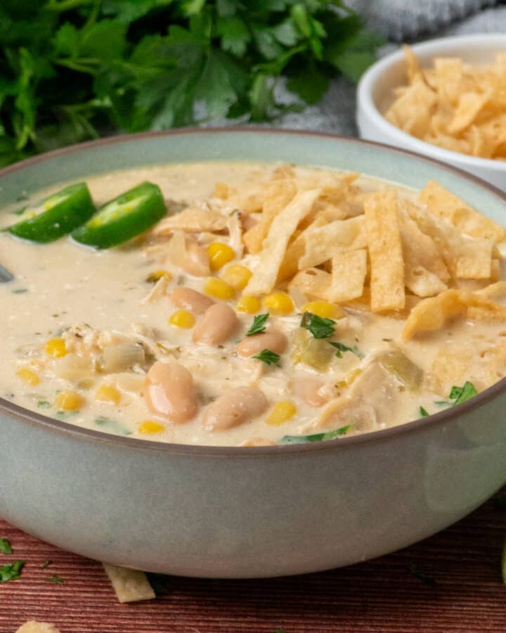 A bowl of crock pot white chicken chili garnished with tortilla strips.