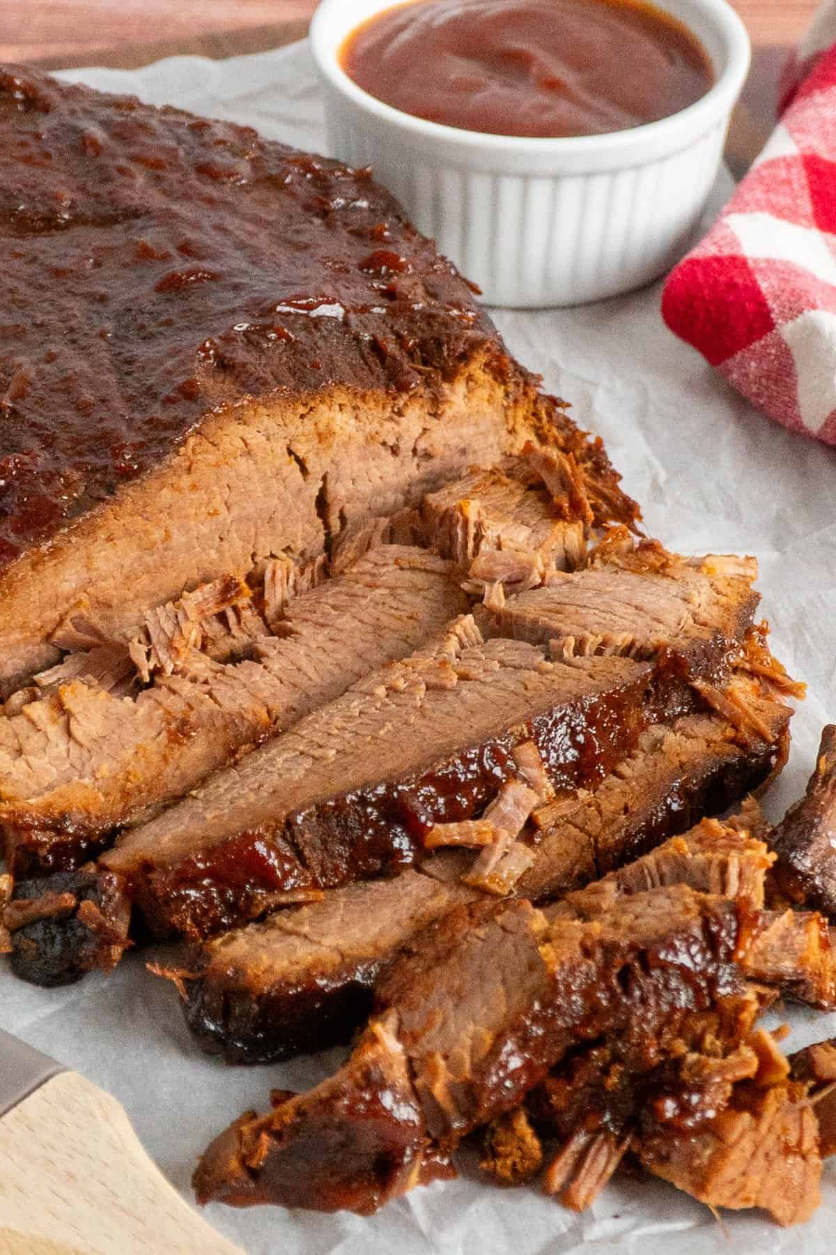 Sliced slow cooker brisket with BBQ sauce on top.