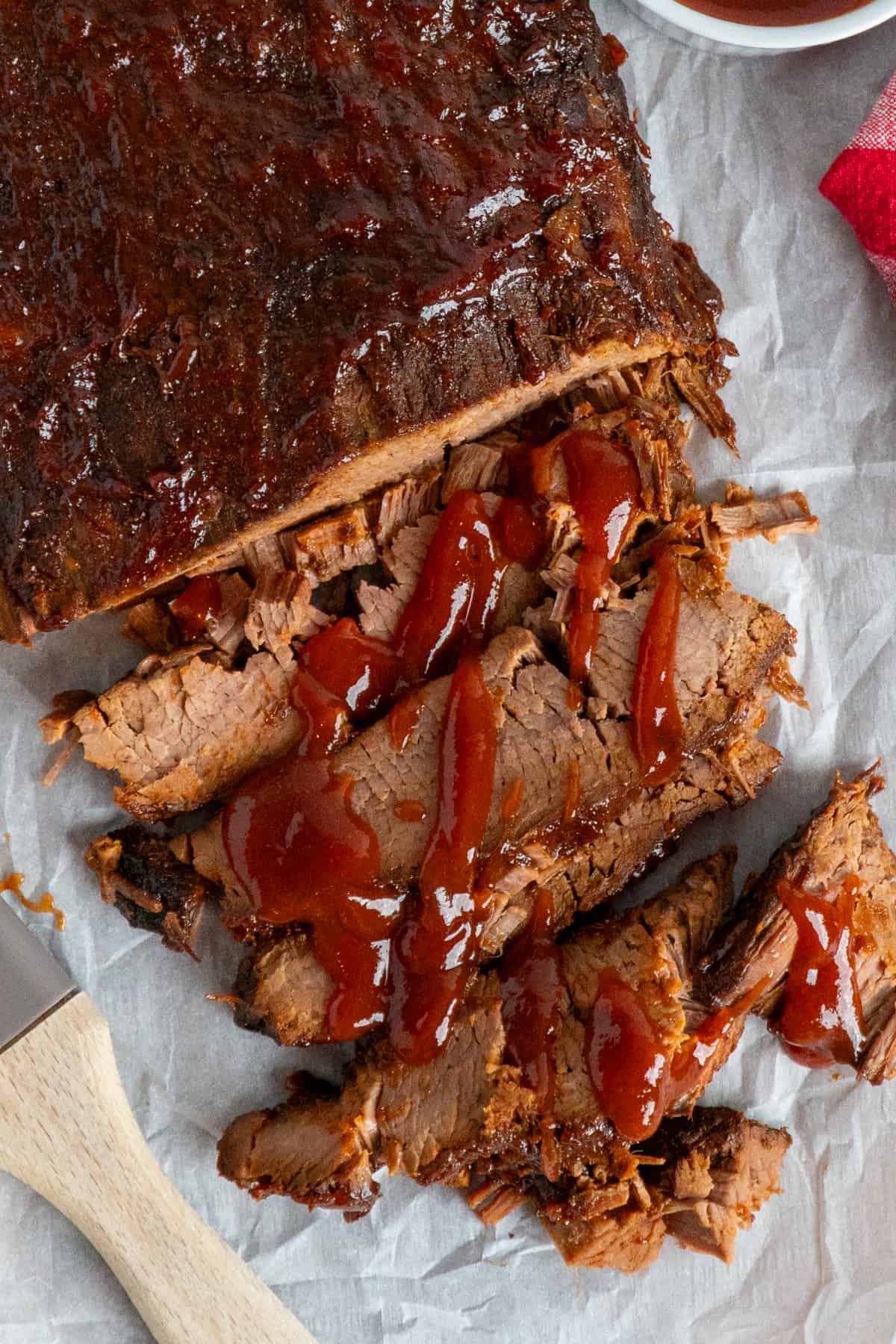 Overhead look at sliced brisket with BBQ sauce on top.