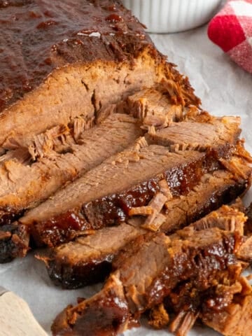 Sliced slow cooker brisket with BBQ sauce on top.