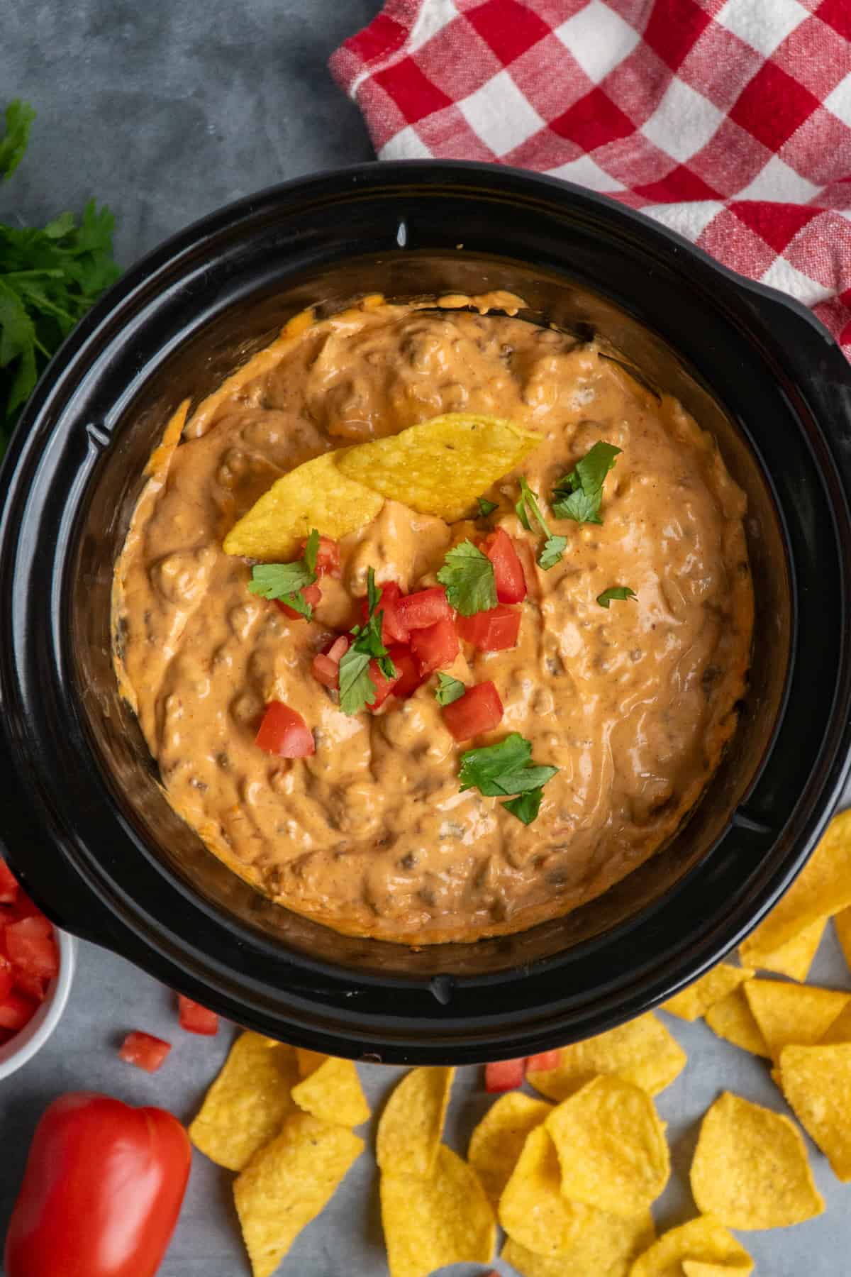 Overhead look at taco dip in a crock pot garnished with tomatoes and cilantro.