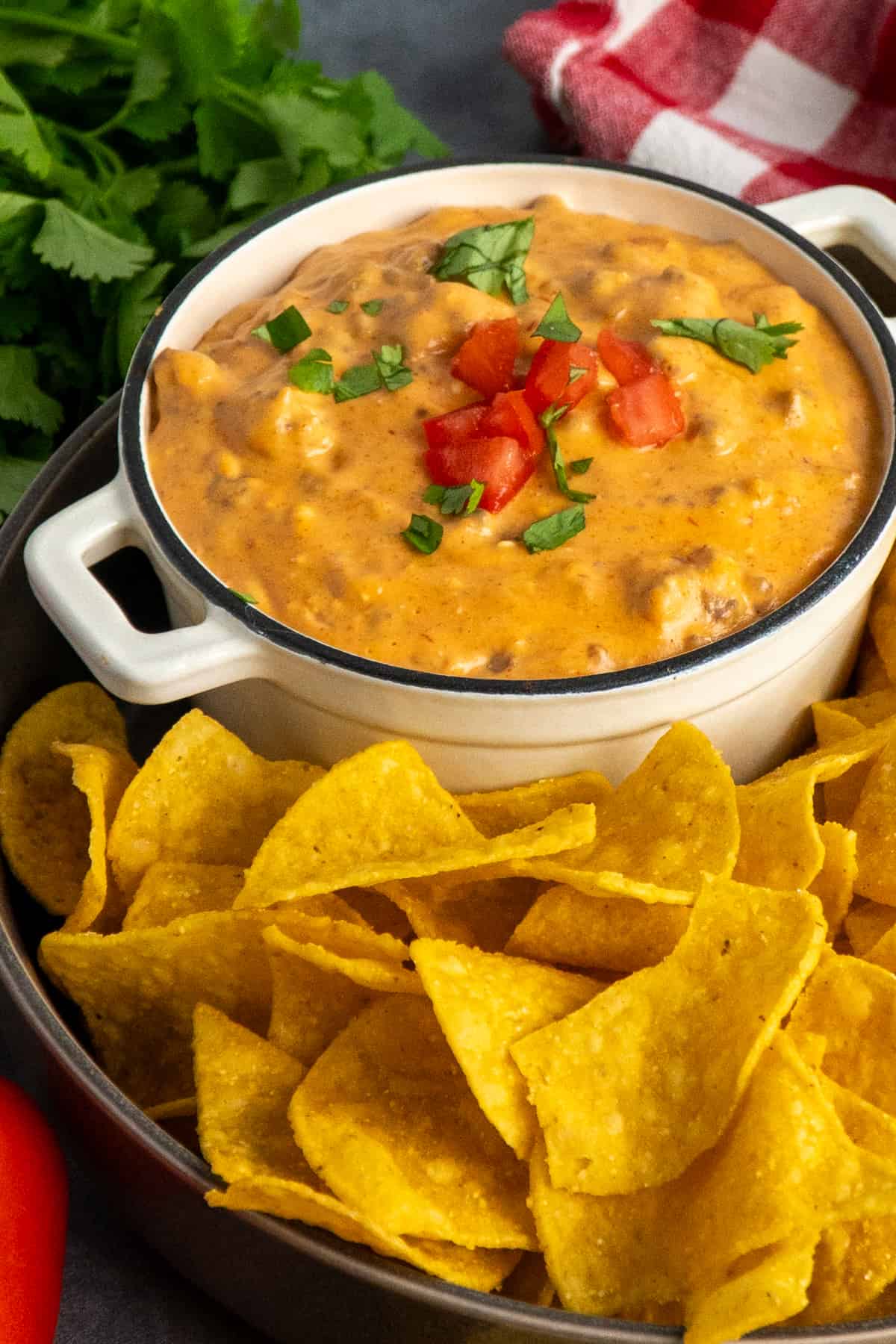 Side view of slow cooker taco dip in a small bowl with tortilla chips.