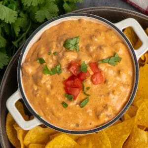 Slow cooker taco dip in a small bowl with tortilla chips.