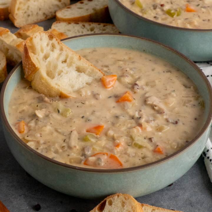 A piece of bread in a bowl of chicken wild rice soup.