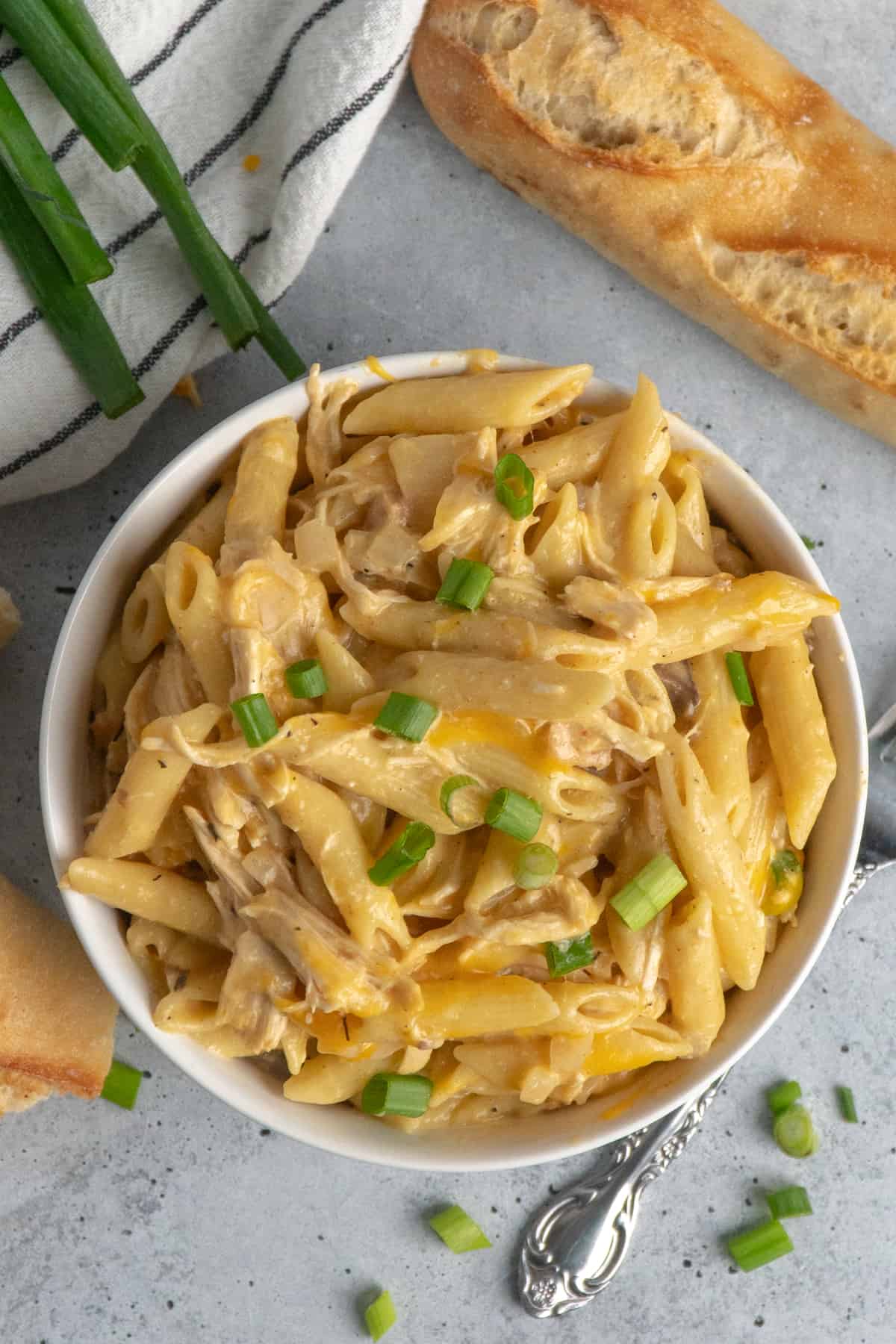 Overhead loka at cheesy chicken penne pasta in a white bowl