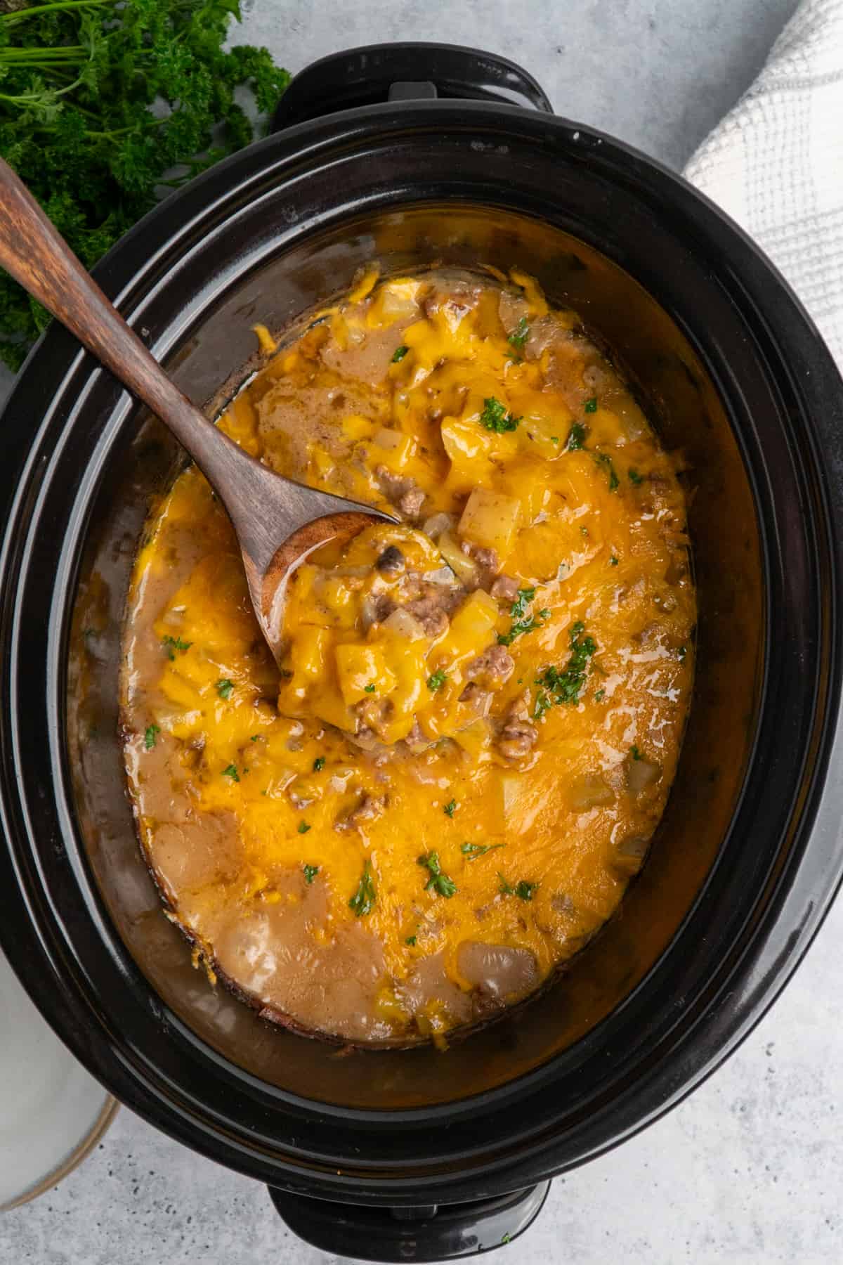 Overhead look at hamburger hash in a crock pot with a wooden spoon