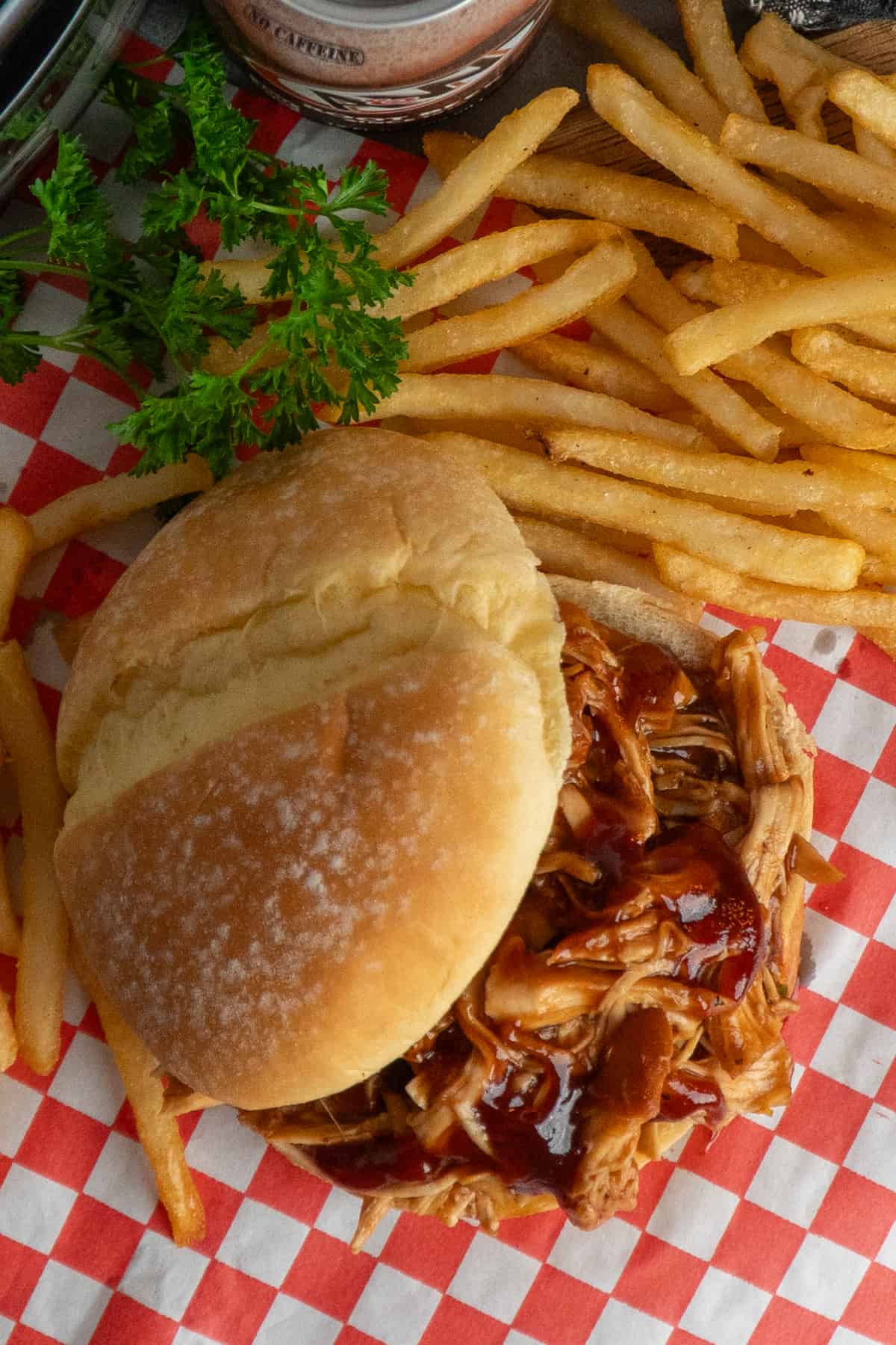 Overhead look at slow cooker root beer chicken on a bun with fries on the side