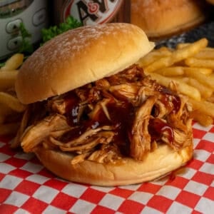 Close-up of slow cooker root beer chicken on a potato bun
