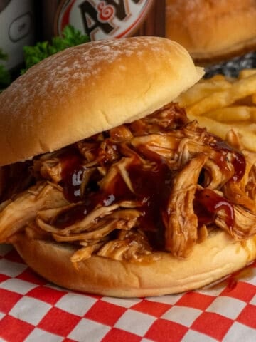 Close-up of slow cooker root beer chicken on a potato bun