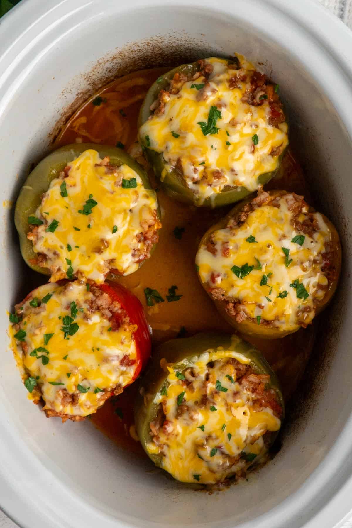 Overhead look at stuffed peppers topped with cheese in a slow cooker