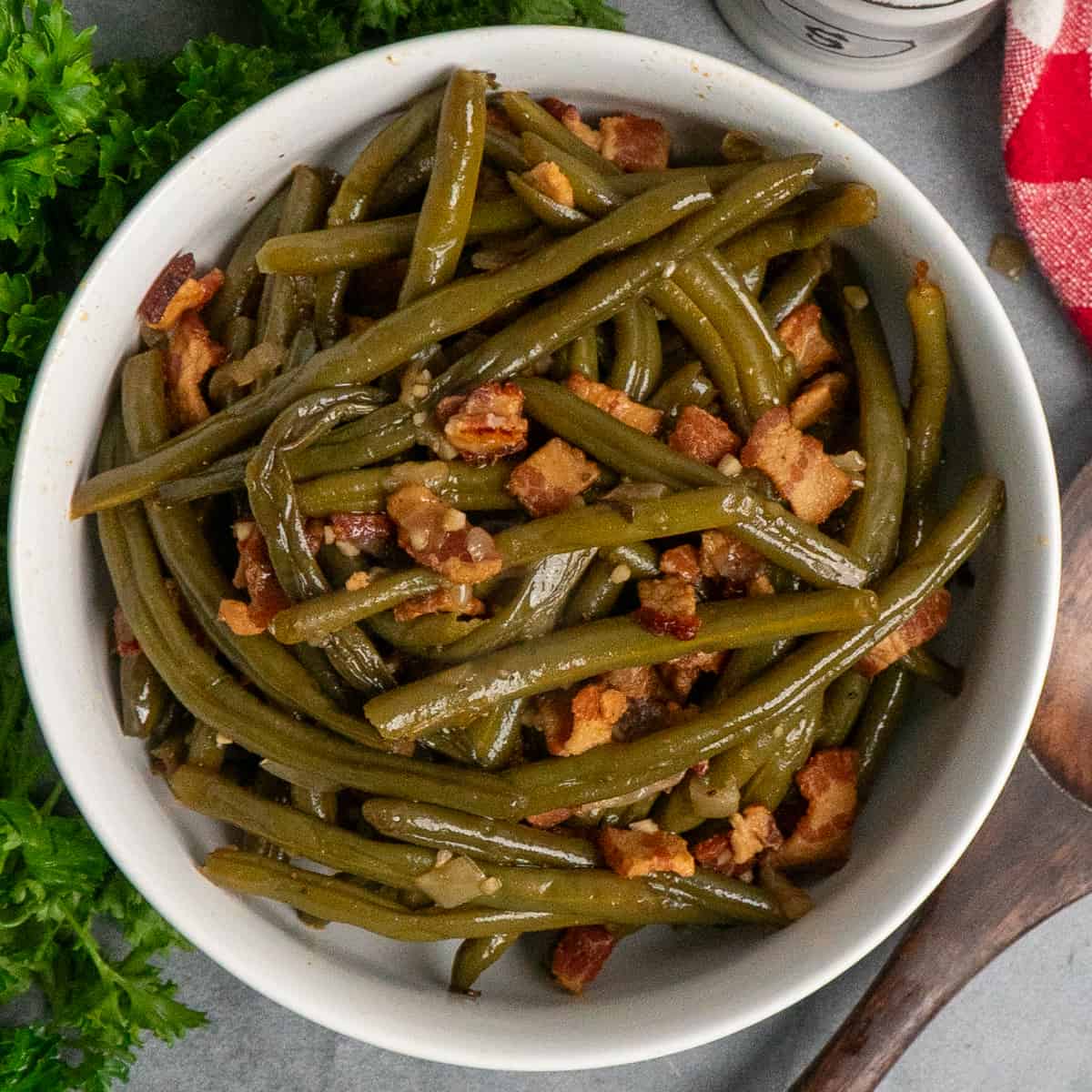 Green beans with bacon in a white bowl.