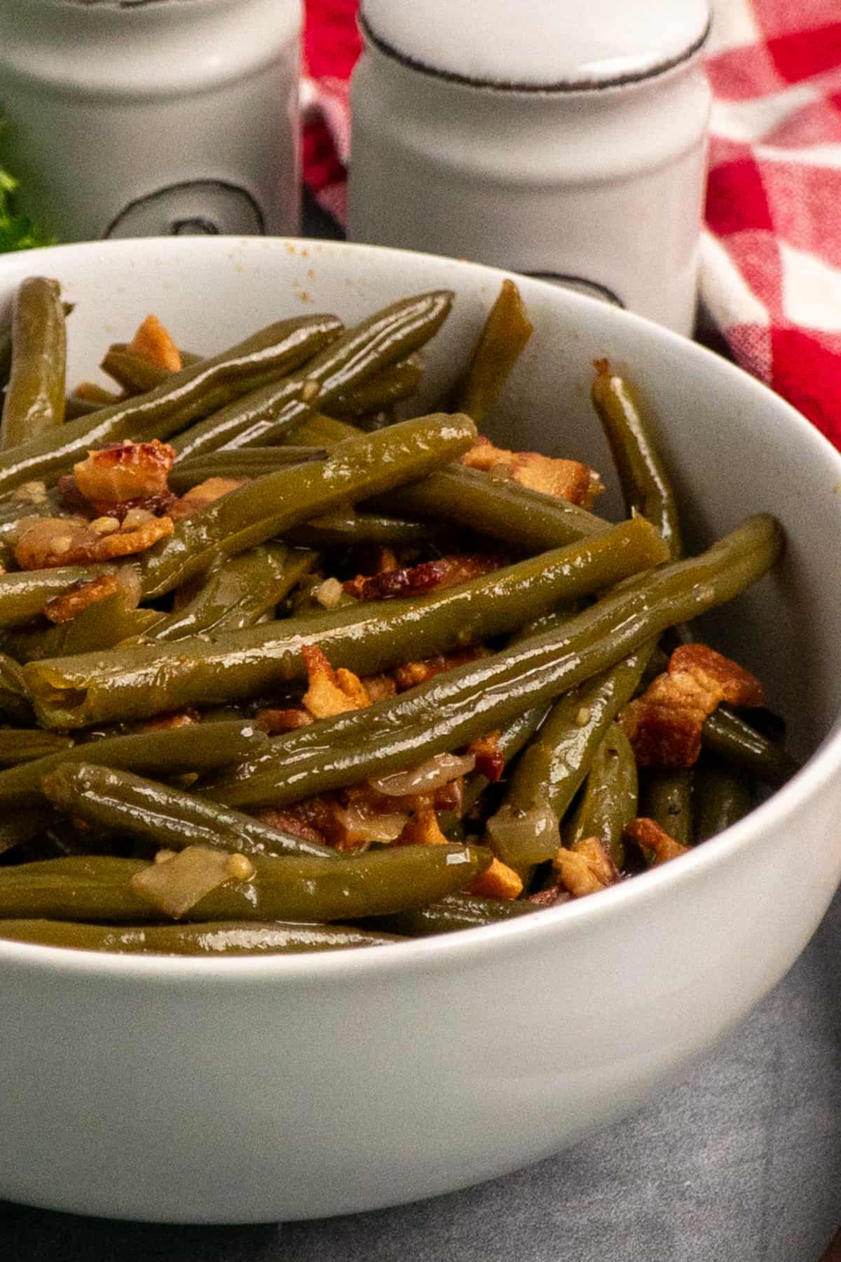 Side view of green beans with bacon in a white bowl.