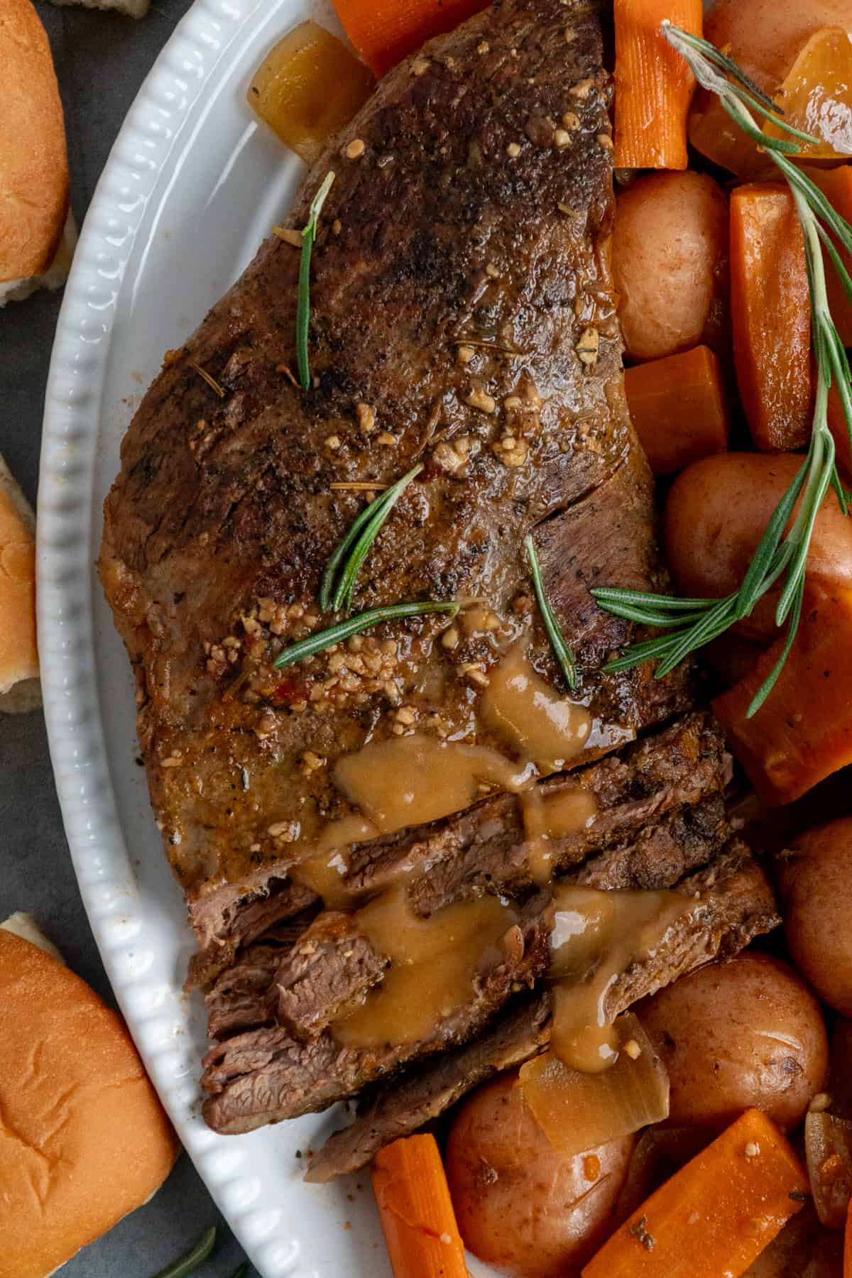Tri tip roast on a serving platter with carrots and potatoes.