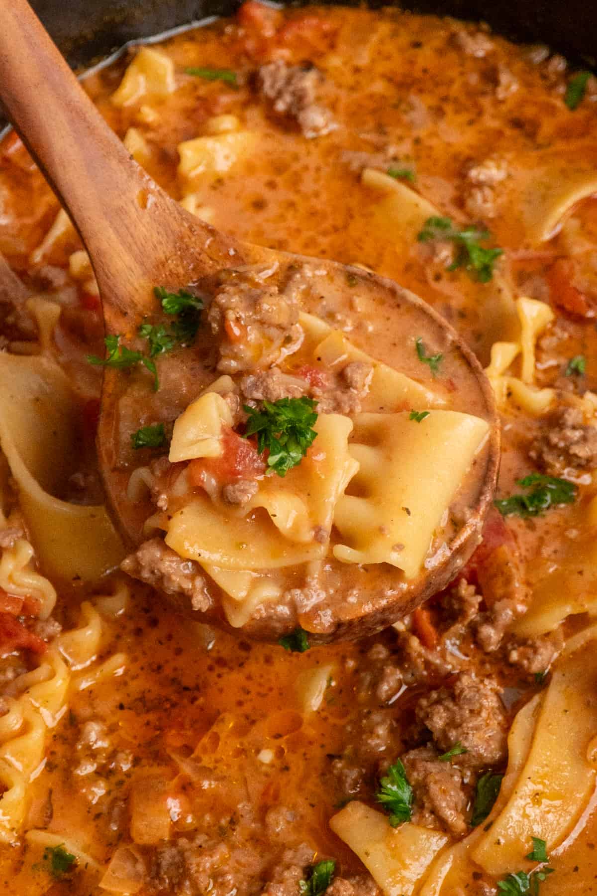 Close up of a wooden ladle scooping lasagna soup.