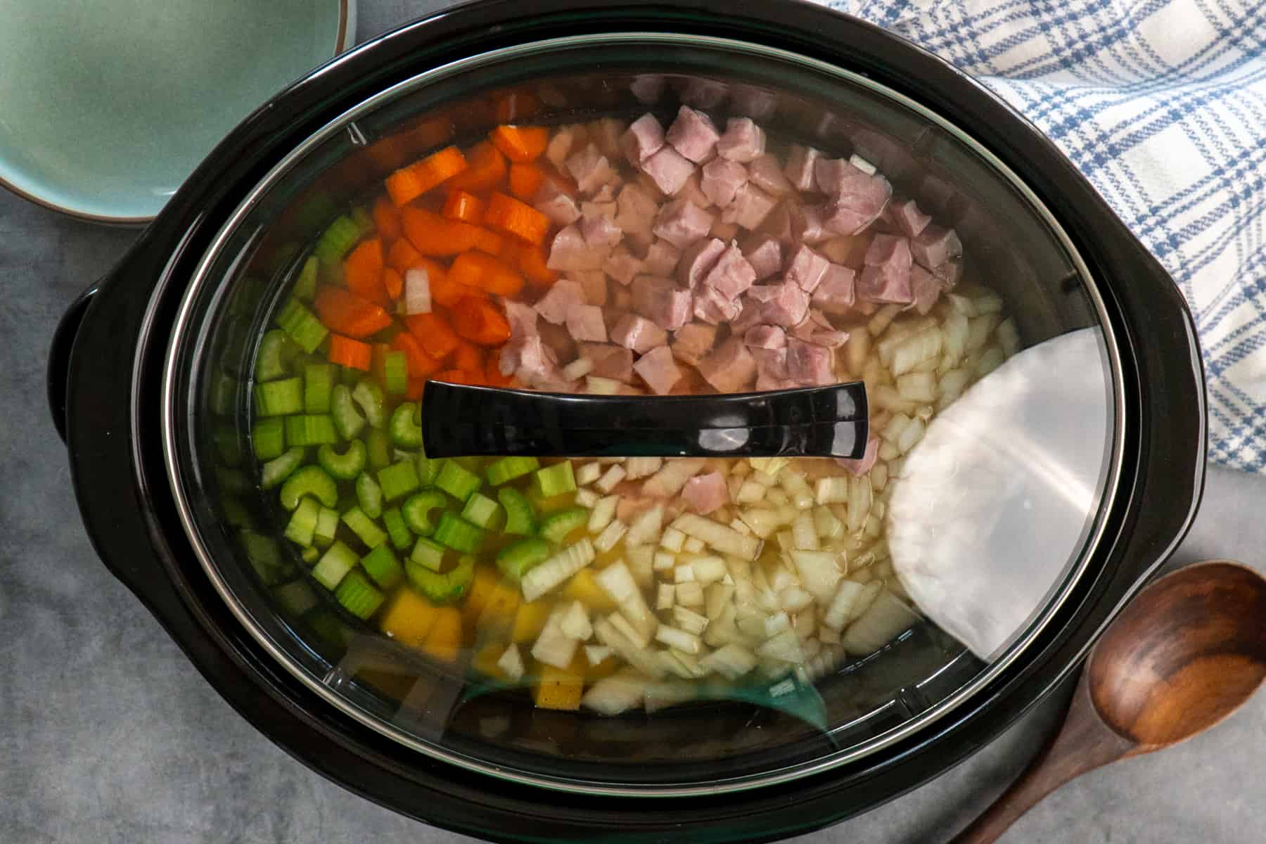 Ham and veggies in a crock pot with the lid on it.