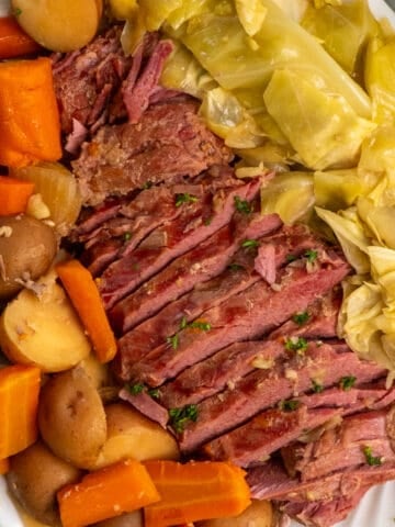 Close up of crock pot corned beef and cabbage on a oval plate.